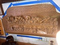 Full view of wooden carving of The Last Supper with textured background and detailed figures seated at a table.