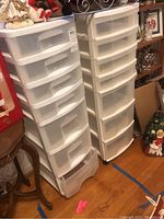 Photo showing two tall plastic storage containers on wheels, each having six drawers, white color with translucent fronts.