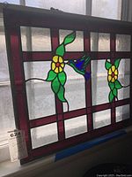 Full view of stained glass panel showing overall design, colors, and size against a window.