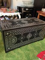 Front and top angle view of dark wood storage trunk with white inlaid carved patterns