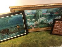 Three pieces of framed wall art, including rural rain canvas, floral pond canvas, and a wood-framed miniature display.