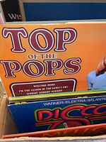 View of boxed vinyl albums showing colorful album covers including 'Top of the Pops' with a yellow background and partial image of a person.