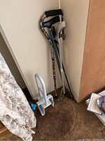 Overall lot view showing two adjustable florally patterned canes, two metal forearm crutches, and the bathtub support.