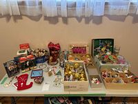 Full view of the Christmas ornaments collection spread on a table, showing various boxed and loose ornaments, two tree toppers, and small decor items.