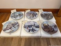 Six Keirstead collector plates displayed on their white boxes with Certificates of Authenticity visible on top.