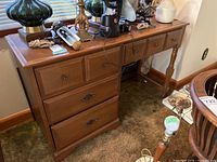 Baronet wooden desk showing left side with four drawers and turned legs on right side, surface covered with non-included items