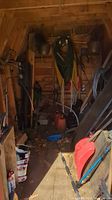 Shelved gardening supplies, hoses coiled, various hand tools hanging on walls of shed