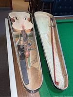 Violin and bow placed inside the open wooden case showing overall wear and condition
