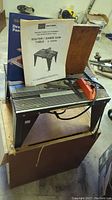 Full view of the Sears Craftsman Router/Sabre Saw Table mounted on a large wood box with instruction manuals placed on top.