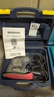 Mastercraft detail sander/polisher placed inside its blue carrying case with the manual upright inside the case.