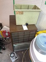 Full view of the Mastercraft D28 dehumidifier showing the plastic water collection tank with a valve on top, and the brown and beige main unit below with vents and controls.