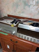 Three audio components placed on wooden surface: Yamaha CT-610 II tuner with manuals and cables, Realistic LAB-1500 turntable, and EICO Cortina amplifier.