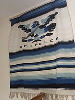 Woven cotton beach blanket with stylized bird and ACAPULCO text, striped pattern in blues and whites