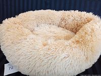 Front view of a soft, fluffy, pale yellow donut style pet bed.