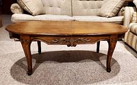 Front view of wooden coffee table showing carved apron details and curved legs.