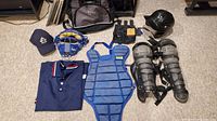 Full lot layout showing chest protector, shin guards, face mask, cap, polo shirt, wrist guard, helmet, ball bag, and small pouch on carpeted floor.