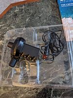Black low pressure inflator device with power cord placed inside a clear plastic tray.