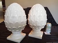 Pair of large white ceramic standing pine cones, front view with a soda can for scale.