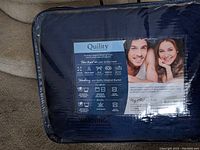 Photo of Quility weighted blanket in packaging showing label with product details, washing instructions, and promotional image.