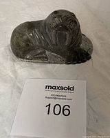 Frontal view of the dark stone walrus carving showing facial details and tusks.