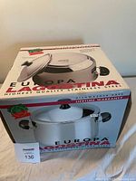 Box of Lagostina Europa 24 cm covered stockpot showing brand and dishwasher safe, lifetime warranty labels.