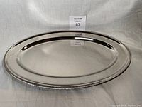 Full view of oval stainless steel platter with polished finish and ribbed rim detail