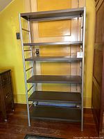 Front view of the metal shelving unit showing six shelves with a faux wood finish and metal frame.