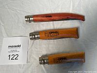 Three closed folding knives with wood handles and Virobloc locking collars, showing different handle wood tones and brand stamps.
