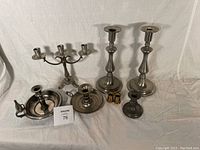 Set of all pewter candleware items displayed together including candelabra, candlesticks, candleholders, and candle sleeves.
