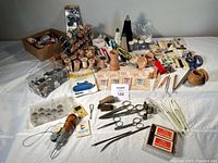 Overview photo showing the full sewing notions lot including wooden spools, scissors, buttons, bobbins, thimbles, tape measure, needle threader, and storage containers.