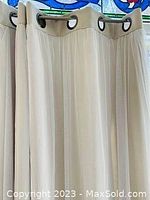 Close-up of cream-colored blackout curtain with metal grommets, showing texture and color.