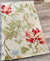 Top view of the carpet showing floral pattern with red, green, and blue flowers on a beige background.