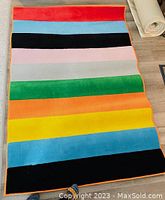 Photo showing a colorful striped Ikea carpet laid out on wooden floor, displaying the full length and colors of the carpet.