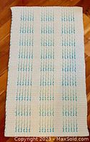 Photo of light cream colored carpet with aquamarine pattern showing textured fabric and design.