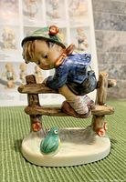 Front view of the 'Retreat to Safety' figurine showing the child climbing a wooden fence with a bird below.