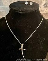 Full view of cross necklace and faux diamond earrings on black display bust