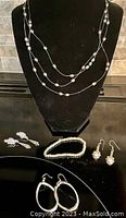 Full view of the lot showing all jewelry pieces including layered grey pearl necklace, pearl bracelet, clip-on earrings, and three pairs of silver-tone earrings.