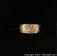Close-up image of silver ring showing intricate West Coast raven design on band.