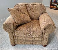 Front view of the beige paisley upholstered armchair including matching cushion on seat.