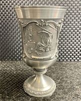 Side view of the pewter goblet showing detailed embossed scene featuring a person sitting under an umbrella and other workshop tools, marked 'Durame Port'