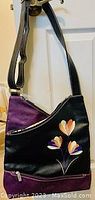 Front of black Espe purse with floral design and black adjustable strap