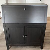 Closed black IKEA secretary desk with a drop-front panel and two lower doors