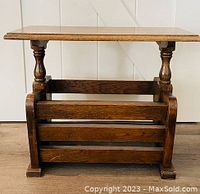 Front view of the antique side table showing solid oak build, flat top, turned legs, and magazine rack with slatted sides.