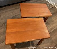 Two solid Danish teak wood end tables shown from an overhead angle on a laminate floor