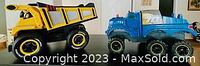 Side view of yellow Fisher-Price dump truck and blue Tonka truck.
