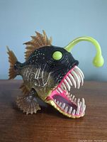 Anglerfish toy facing front-left angle showing open mouth with teeth, eyes, lure and top fin details.