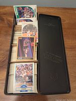 Photo showing several 1990s basketball cards displayed inside black Johnny Walker Black Label tin, cards from NBA Hoops, Fleer, Skybox visible.