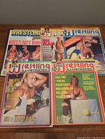 Five wrestling magazines displayed side by side showing full covers with different wrestlers from late 1980s to early 1990s.
