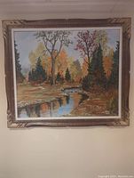 Full view of the framed fall colors landscape painting featuring trees and water.