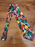 Front view of necktie showing colorful pattern of Snoopy with Christmas ornaments on black background.